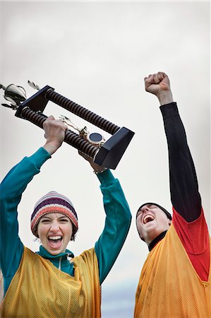 simsearch:6102-06336816,k - Caucasian woman and man celebrating a team win in a sporting event with a trophy in hand. Foto de stock - Sin royalties Premium, Código: 6118-09130018