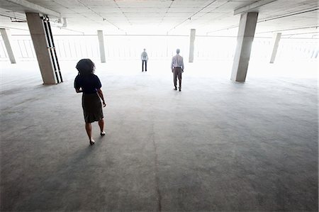 simsearch:6118-09139404,k - Business people walking toward windows in a large empty office raw space. Photographie de stock - Premium Libres de Droits, Code: 6118-09139389