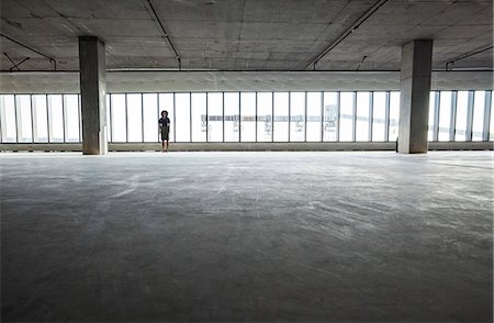 simsearch:6118-09139404,k - Business woman standing near windows in a new empty raw office space. Photographie de stock - Premium Libres de Droits, Code: 6118-09139397