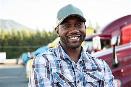 satisfied african american man - Black man truck driver near his truck parked in a parking lot at a truck stop Stock Photo - Premium Royalty-Free, Code: 6118-09139329