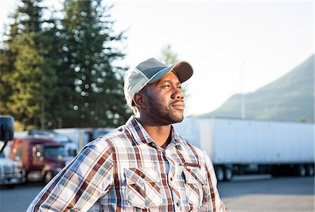 Black man truck driver near his truck parked in a parking lot at a truck stop Stock Photo - Premium Royalty-Free, Code: 6118-09139337