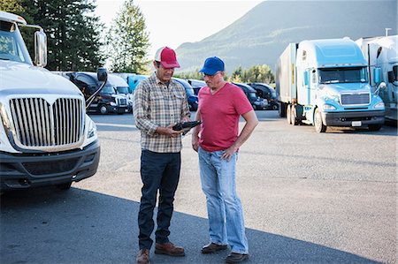 Truck driver team of Caucasian drivers going over dispatch information in the parking lot of a truck stop. Foto de stock - Sin royalties Premium, Código: 6118-09139336