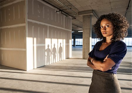 renovations blueprints - Black businesswoman  standing in an empty raw office space. Stock Photo - Premium Royalty-Free, Code: 6118-09139445