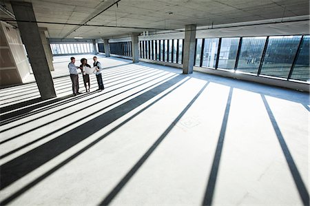 simsearch:6118-09139404,k - Mixed race team of business people touring a new empty raw office space. Photographie de stock - Premium Libres de Droits, Code: 6118-09139401