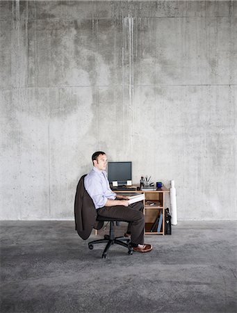 simsearch:6118-09139404,k - Business man sitting at a small desk in a large empty raw office space. Photographie de stock - Premium Libres de Droits, Code: 6118-09139411