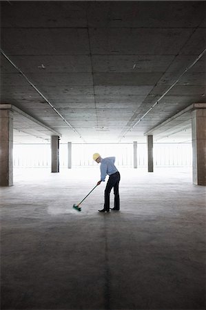 simsearch:6118-09139404,k - Asian businessman cleaning up with a broom in a large empty raw office space. Photographie de stock - Premium Libres de Droits, Code: 6118-09139417