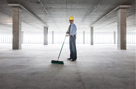 simsearch:6118-09139404,k - Asian businessman cleaning up with a broom in a large empty raw office space. Photographie de stock - Premium Libres de Droits, Code: 6118-09139418