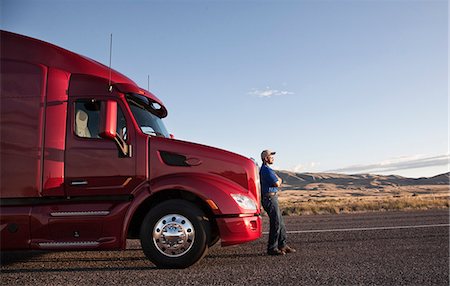 Truck driver leaning on the grill of his  commercial truck. Foto de stock - Sin royalties Premium, Código: 6118-09139560