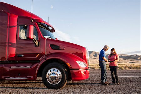 Husband and wife driving team checking their itinerary while standing in front of their  commercial truck. Foto de stock - Sin royalties Premium, Código: 6118-09139561
