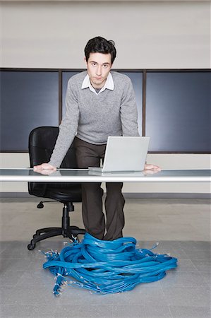 Caucasian businessman wrapped up in CAT 5 computer cables from a computer server farm. Stock Photo - Premium Royalty-Free, Code: 6118-09139649