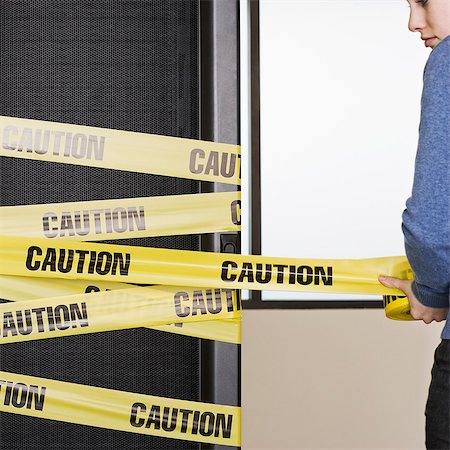 simsearch:6118-09139628,k - Computer server rack being wrapped with yellow caution tape by a Caucasian woman. Foto de stock - Sin royalties Premium, Código: 6118-09139658
