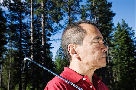 senior japanese golfer - A senior golfer ready to approach the next shot on a golf course. Stock Photo - Premium Royalty-Free, Code: 6118-09139691