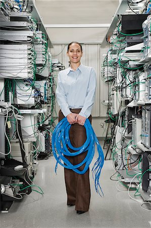 Female computer technician holding CAT 5 cables and standing in the aisle of a computer server farm. Photographie de stock - Premium Libres de Droits, Code: 6118-09139627