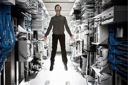 A Caucasian man lab technician appearing to float through air in the aisle of a computer server farm. Stock Photo - Premium Royalty-Free, Code: 6118-09139637