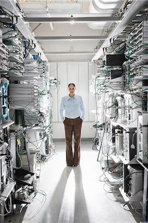 simsearch:6118-09139628,k - Caucasian woman technician working in the aisle of a computer server farm. Foto de stock - Sin royalties Premium, Código: 6118-09139636