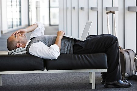 Exhausted businessman taking a short break laying on a bench in an office lobby. Stock Photo - Premium Royalty-Free, Code: 6118-09139753