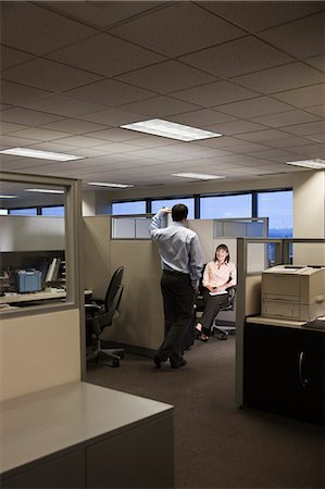 simsearch:6118-09139986,k - Two young business people working into the evening in a cubicle office set up. Foto de stock - Sin royalties Premium, Código: 6118-09139813