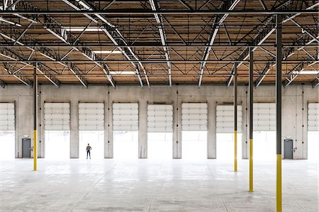 simsearch:6118-09166274,k - Owner silhouetted and standing in a loading dock door for a new empty warehouse. Photographie de stock - Premium Libres de Droits, Code: 6118-09139945