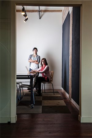 simsearch:6118-09139986,k - Caucasian woman and Asian woman working on a laptop computer in a small conference room. Foto de stock - Sin royalties Premium, Código: 6118-09139987