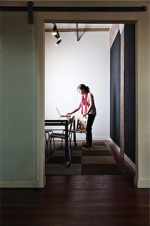 simsearch:6118-09139986,k - Caucasian woman working on a laptop computer in a small conference room. Foto de stock - Sin royalties Premium, Código: 6118-09139986