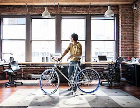 simsearch:6118-09147986,k - Hispanic man at his office workstation with a bicycle. Fotografie stock - Premium Royalty-Free, Codice: 6118-09139997