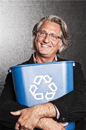 Studio portrait of Caucasian man actor holding a blue recycling bin to his chest. Stock Photo - Premium Royalty-Free, Code: 6118-09139910