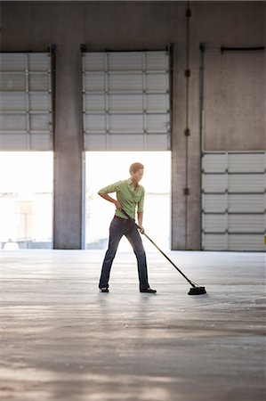 picture of a lady sweeping the floor - Black woman sweeping up in an empty warehouse space. Stock Photo - Premium Royalty-Free, Code: 6118-09139935