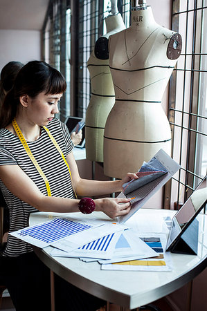 Japanese female fashion designer working in her studio, sitting at table, looking at fabric samples. Foto de stock - Sin royalties Premium, Código: 6118-09200157