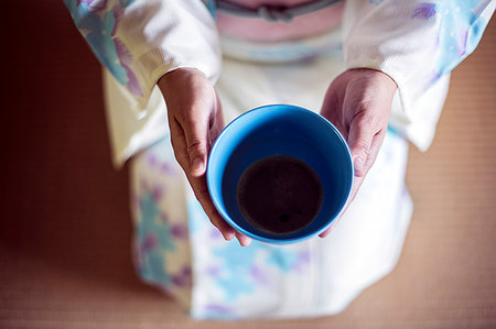 simsearch:6118-09200260,k - High angle close up of Japanese woman wearing traditional white kimono with blue floral pattern kneeling on floor during tea ceremony, holding blue tea bowl. Photographie de stock - Premium Libres de Droits, Code: 6118-09200246