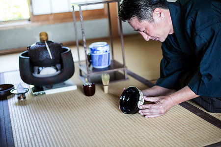 simsearch:6118-09200284,k - Japanese man wearing traditional kimono kneeling on floor, holding tea bowl, during tea ceremony. Stock Photo - Premium Royalty-Free, Code: 6118-09200259
