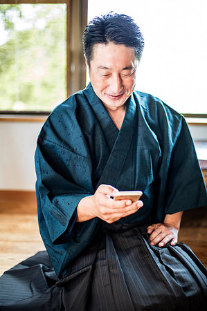 simsearch:6118-09200260,k - Japanese man wearing kimono sitting on floor in traditional Japanese house, using mobile phone. Photographie de stock - Premium Libres de Droits, Code: 6118-09200285