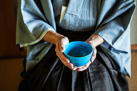 simsearch:6118-09200284,k - High angle close up of Japanese man wearing traditional kimono kneeling on floor holding blue tea bowl during tea ceremony. Stock Photo - Premium Royalty-Free, Code: 6118-09200229