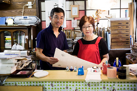 simsearch:6118-09200406,k - A man and woman, partners in a traditional business,  behind a counter in a shop, displays of traditional handmade fibre washi paper. Foto de stock - Sin royalties Premium, Código: 6118-09200417