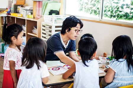 Male teacher talking to group of children at a table n a Japanese preschool. Stock Photo - Premium Royalty-Free, Code: 6118-09200523