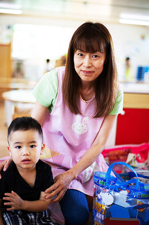 Female teacher and boy in a Japanese preschool, smiling at camera. Stock Photo - Premium Royalty-Free, Code: 6118-09200538
