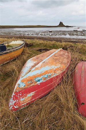 Old brightly painted fishing boats and Lindisfarne Castle in winter, Holy Island, Northumberland, England, United Kingdom, Europe Foto de stock - Royalty Free Premium, Número: 6119-07781089