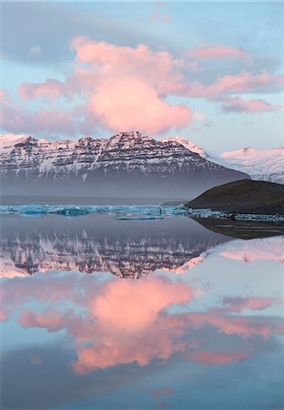 suourland - Panoramic view across the calm water of Jokulsarlon glacial lagoon towards snow-capped mountains and icebergs bathed in the last light of a winter's afternoon, at the head of the Breidamerkurjokull Glacier on the edge of the Vatnajokull National Park, South Iceland, Iceland, Polar Regions Stock Photo - Premium Royalty-Free, Code: 6119-07781108