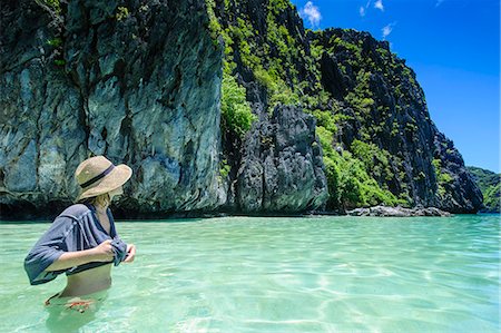 philippines - Woman standing in the crystal clear water and enjoys the stunning scenery  in the Bacuit archipelago, Palawan, Philippines, Southeast Asia, Asia Stock Photo - Premium Royalty-Free, Code: 6119-07735073