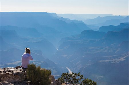 Woman sitting on the cliff of the desert view point over the Grand Canyon, UNESCO World Heritage Site, Arizona, United States of America, North America Stock Photo - Premium Royalty-Free, Code: 6119-07943950