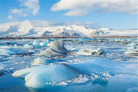 Mountains behind the icebergs locked in the frozen water of Jokulsarlon Iceberg Lagoon, Jokulsarlon, South East Iceland, Iceland, Polar Regions Stock Photo - Premium Royalty-Free, Code: 6119-08081133