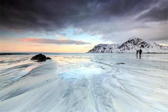 Sunset and hikers on Skagsanden beach surrounded by snow covered mountains, Flakstad, Lofoten Islands, Arctic, Norway, Scandinavia, Europe Stock Photo - Premium Royalty-Free, Image code: 6119-08170191
