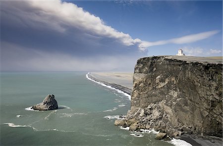 frêne - Headland with lighthouse at Dyrholaey looking towards a black volcanic sand beach stretching 15 miles into the distance and the ash plume of the Eyjafjallajokull eruption, near Vik i Myrdal, southern area, Iceland, Polar Regions Photographie de stock - Premium Libres de Droits, Code: 6119-08266476