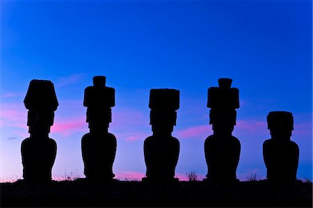 Anakena beach, monolithic giant stone Moai statues of Ahu Nau Nau, four of which have topknots, silhouetted at dusk, Rapa Nui (Easter Island), UNESCO World Heritage Site, Chile, South America Stock Photo - Premium Royalty-Free, Code: 6119-08269322