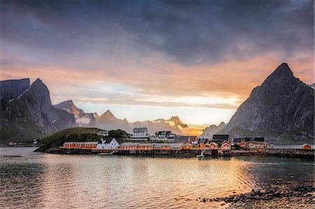 Sunset on the fishing village framed by rocky peaks and sea, Sakrisoya, Nordland county, Lofoten Islands, Arctic, Northern Norway, Scandinavia Europe Stock Photo - Premium Royalty-Free, Code: 6119-08724981