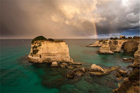 Rainbow frames rocky cliffs known as Faraglioni di Sant'andrea surrounded by turquoise sea, province of Lecce, Apulia, Italy, Europe Photographie de stock - Premium Libres de Droits, Code: 6119-09073968