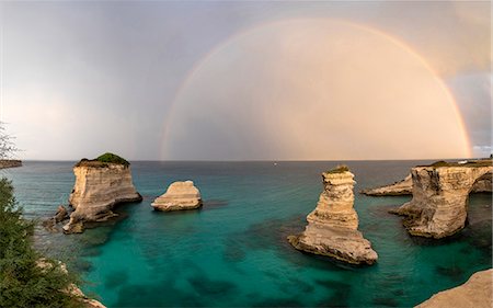 rough ocean - Rainbow frames rocky cliffs known as Faraglioni di Sant'andrea surrounded by turquoise sea, province of Lecce, Apulia, Italy, Europe Stock Photo - Premium Royalty-Free, Code: 6119-09073971