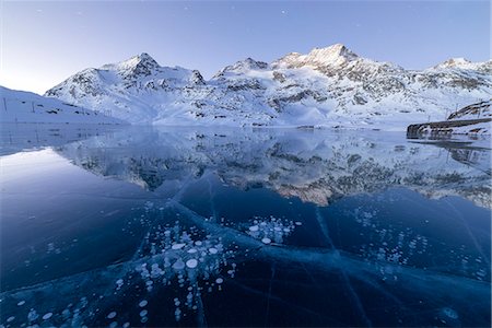 Ice bubbles frame the snowy peaks reflected in Lago Bianco, Bernina Pass, canton of Graubunden, Engadine, Switzerland, Europe Foto de stock - Sin royalties Premium, Código: 6119-09074045