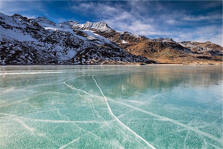 The snowy peaks frame the frozen turquoise water of White Lake (Lago Bianco), Bernina Pass, Canton of Graubunden, Engadine, Switzerland, Europe Stock Photo - Premium Royalty-Free, Code: 6119-09074119