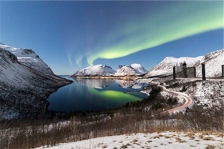Photographer on platform admires the Northern lights (aurora borealis) and stars reflected in the cold sea, Bergsbotn, Senja, Troms, Norway, Scandinavia, Europe Stock Photo - Premium Royalty-Free, Code: 6119-09074129