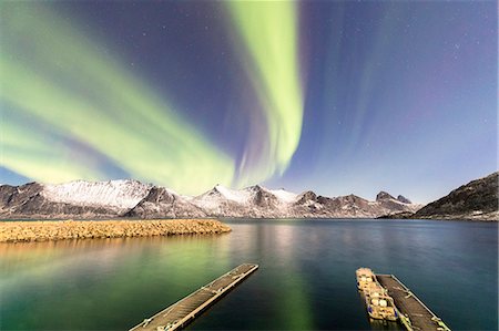Northern lights (aurora borealis) on snowy peaks and icy sea along Mefjorden seen from the village of Mefjordvaer, Senja, Troms, Norway, Scandinavia, Europe Stock Photo - Premium Royalty-Free, Code: 6119-09074131
